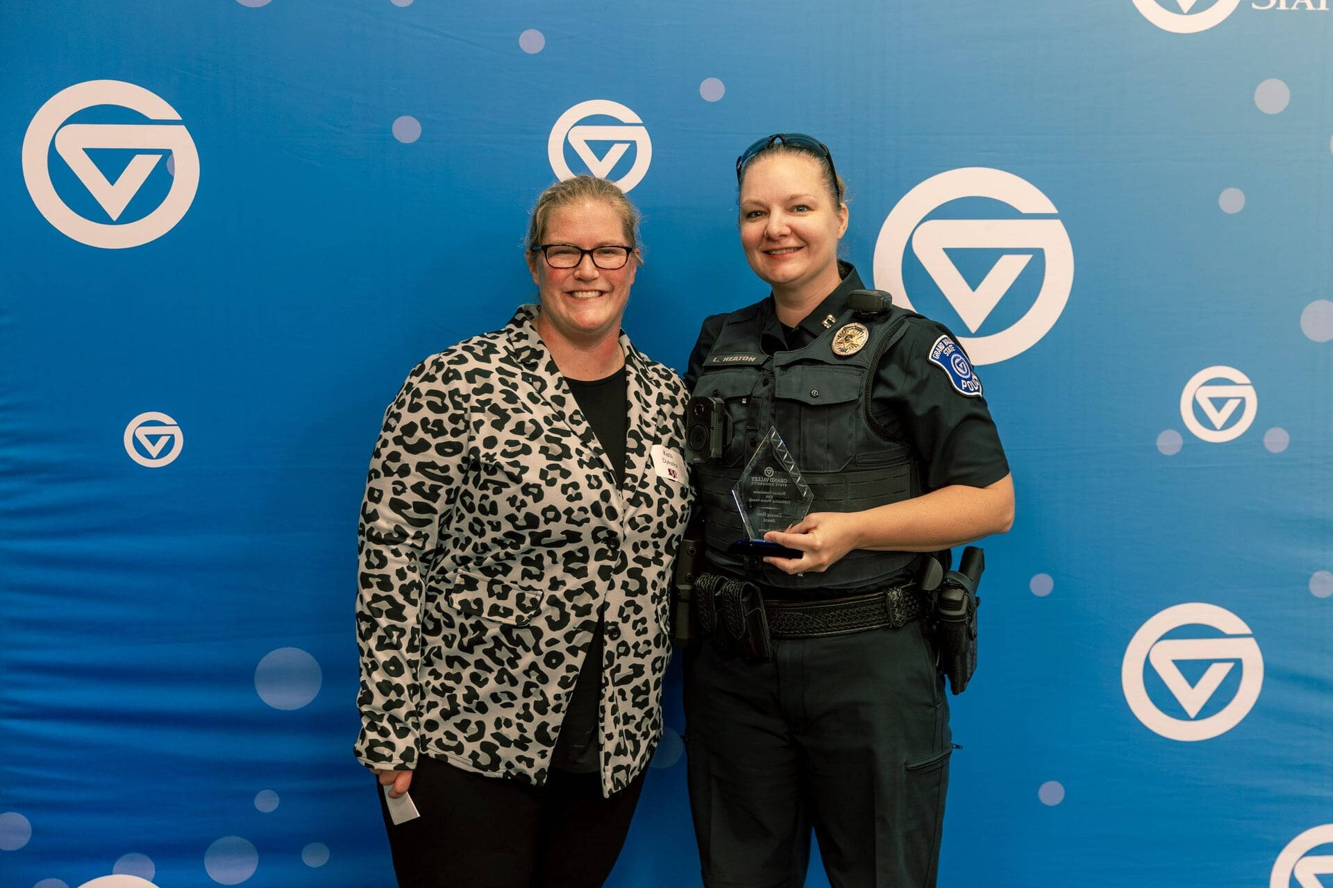 Kelli Dykstra at left with police Capt. Leah Heaton in uniform and she is holding a glass award
